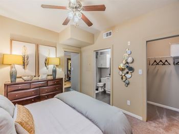 A bedroom with a bed, dresser, and ceiling fan.